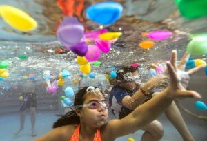 ten-year olds kaitlynn tran of chicago, and michael ramirez of aurora, ill., right, gather plastic eggs floating in the peoria aquaplex pool during an underwater egg hunt in peoria, ill. on saturday, april 19, 2014. (ron johnson/peoria journal star)