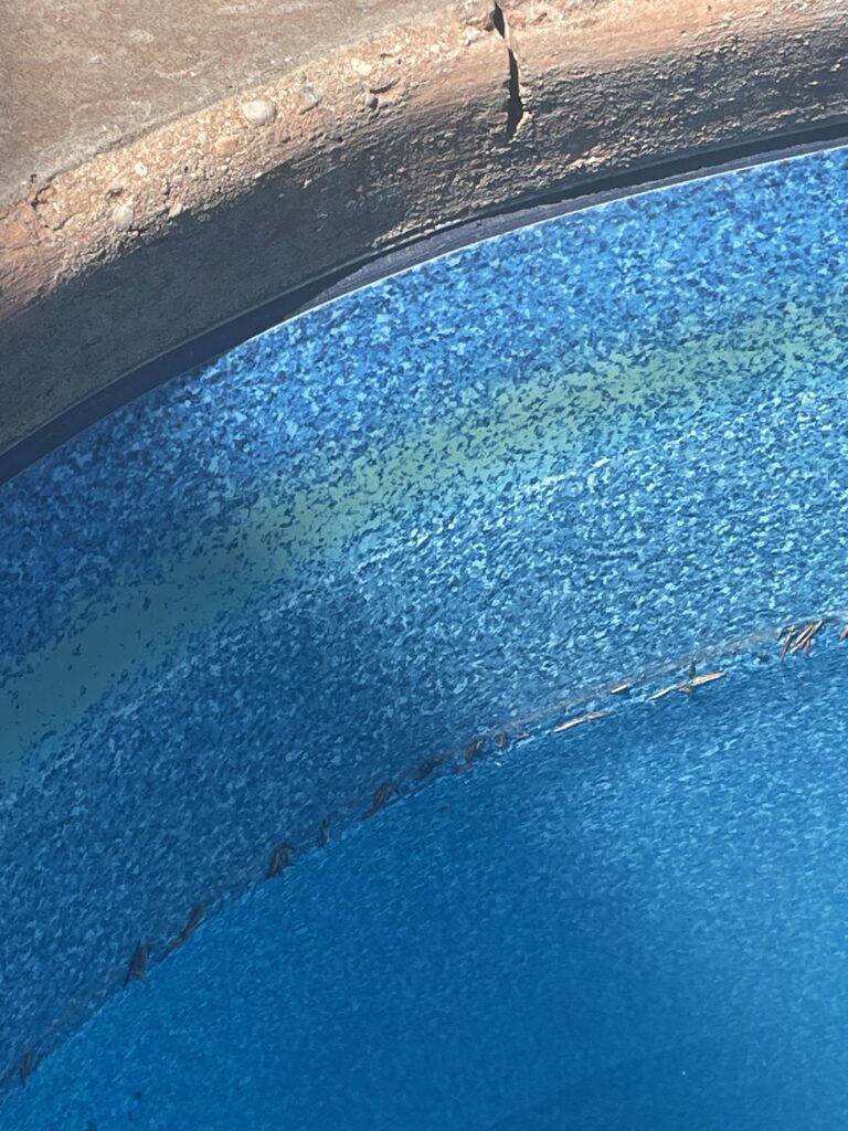 sun staining on the liner of a pool, showcasing a yellow stain or ring of yellow discolouration.