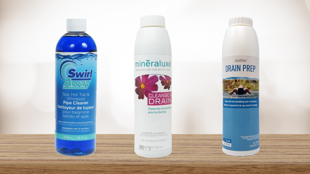 a photo with a white background with light woodgrain at the bottom, showcasing 3 hot tub drain and refill pipe cleaning products. from left to right, swirl away, a blue liquid in a clear bottle with a white lid. in the center, mineraluxe cleanse & drain, a white bottle with a mostly white label with dark pink flowers. on the right, drain prep, a white bottle with a white and lighter blue label.