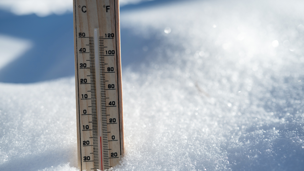 a close up photo of a wooden thermometer in the snow. 