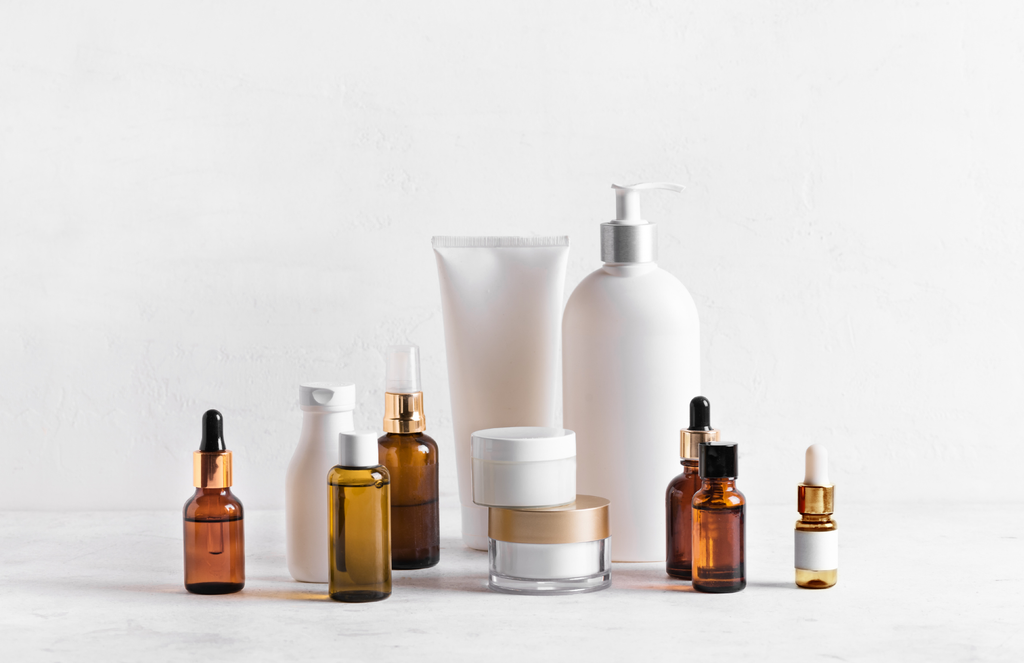 a white marble tabletop with a white background, with an array of unlabeled lotions, sprays, and oils.